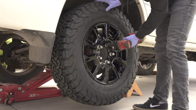 Mechanic Tightening Bolts on A Mounted 33-Inch Off-Road Tire on A Lifted Vehicle