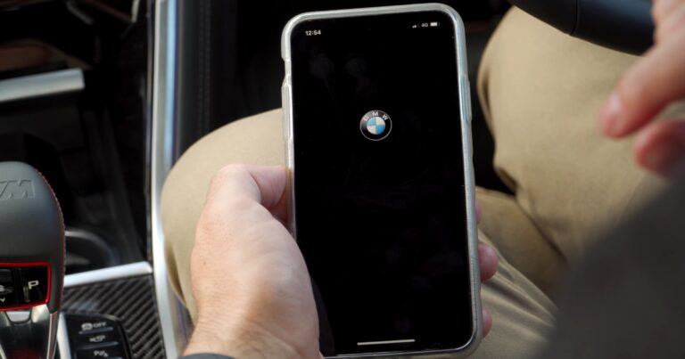 Guy sitting in a BMW car opening an BMW app on a phone