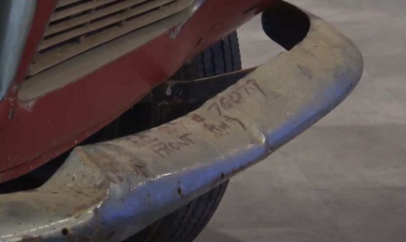 A weathered, vintage car bumper, bearing the number 70079