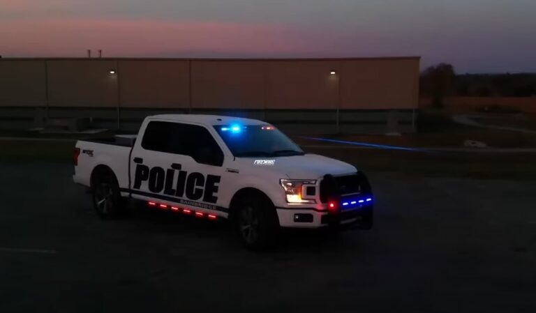 A white police pickup truck with lights flashing