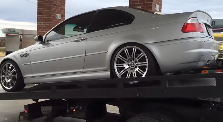 A silver BMW coupe, expertly loaded onto a flatbed tow truck