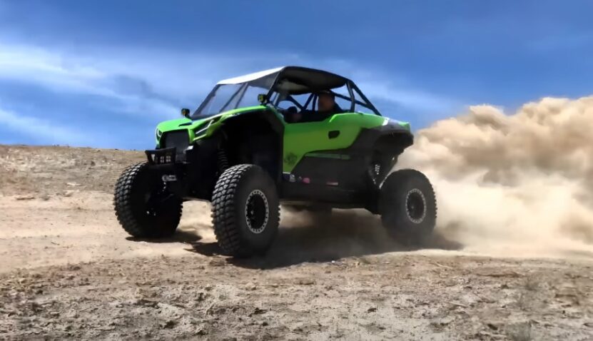 A vibrant green UTV navigates a sandy trail