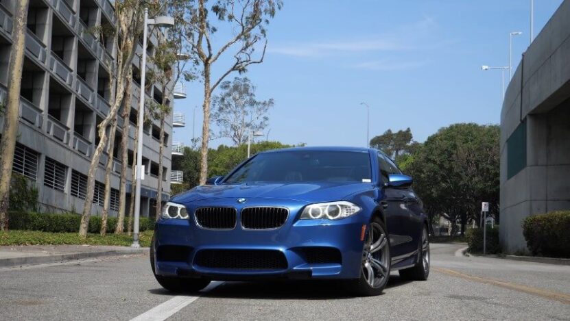 A vibrant blue BMW M5 parked on a city street