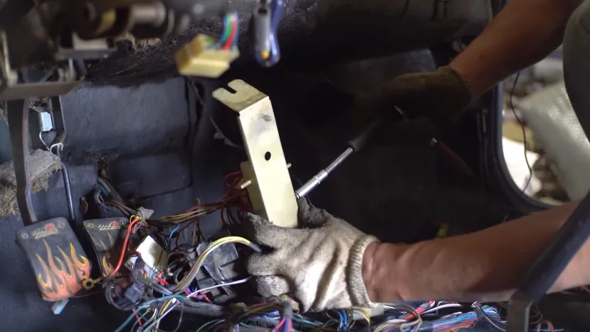 A mechanic works on a vehicle's interior wiring harness