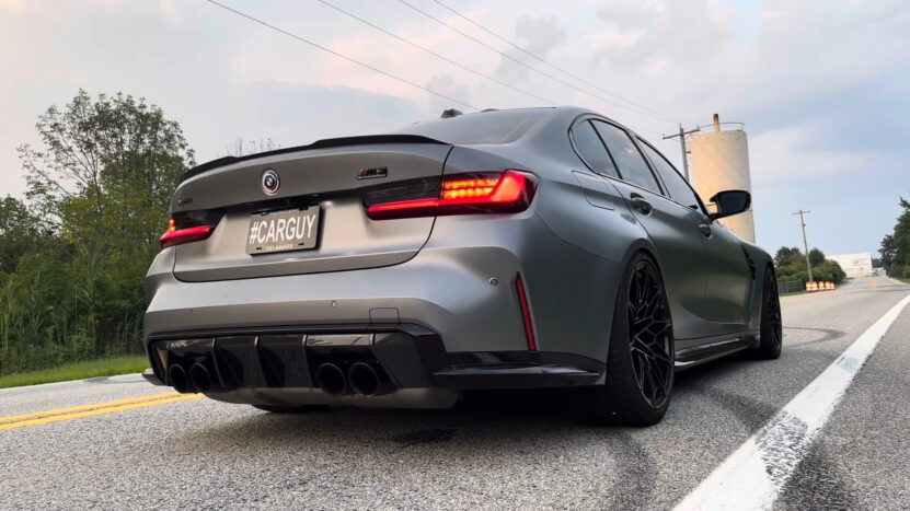 Rear view of a BMW M3 on a road with visible tire marks, taillights on, suggesting launch control was activated