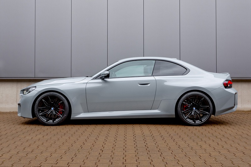 Side profile of a BMW M2 Coupe (G87) parked on a brick surface, available with a manual transmission option