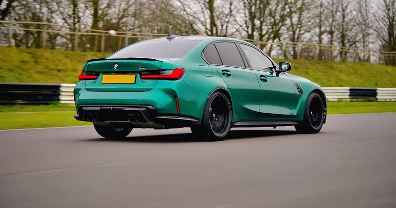 A green BMW M3 G80 sedan driving on a racetrack, known for offering a manual transmission option
