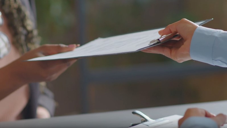 A clipboard is passed, signifying a crucial document exchange