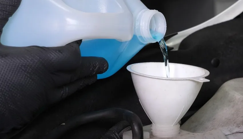 Coolant being poured into a car's reservoir using a funnel