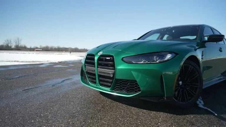 Front view of a green BMW M3 parked on a wet road, showing what it’s like to daily drive a BMW M3 in winter conditions