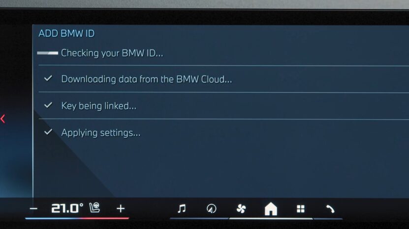 BMW infotainment screen displaying the process of adding a BMW ID, with progress indicators for checking ID, downloading data, linking key, and applying settings