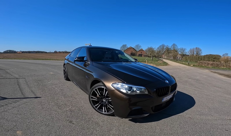 Metallic brown BMW F10 parked outdoors under a clear sky, showcasing the M Sport package and aftermarket wheels