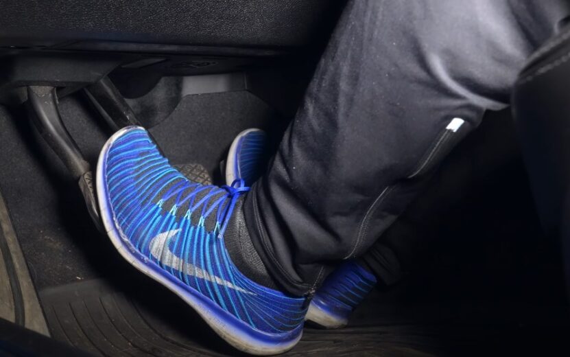 Feet positioned over the car's pedals, ready for operation