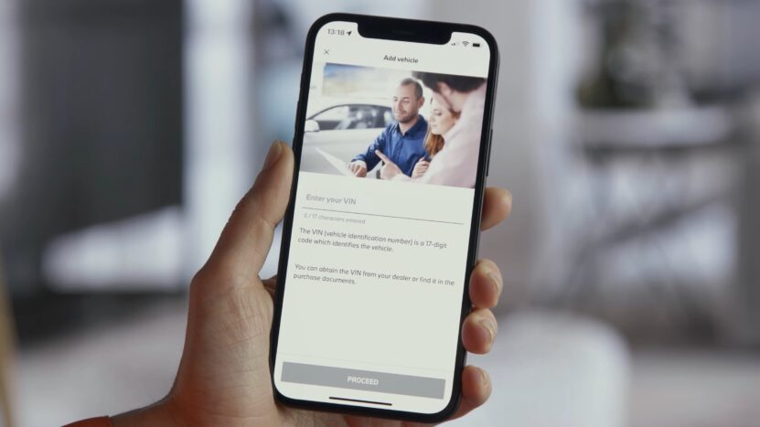 Close-up of a smartphone screen showing the VIN entry screen on the My BMW app, with a couple receiving assistance at a dealership