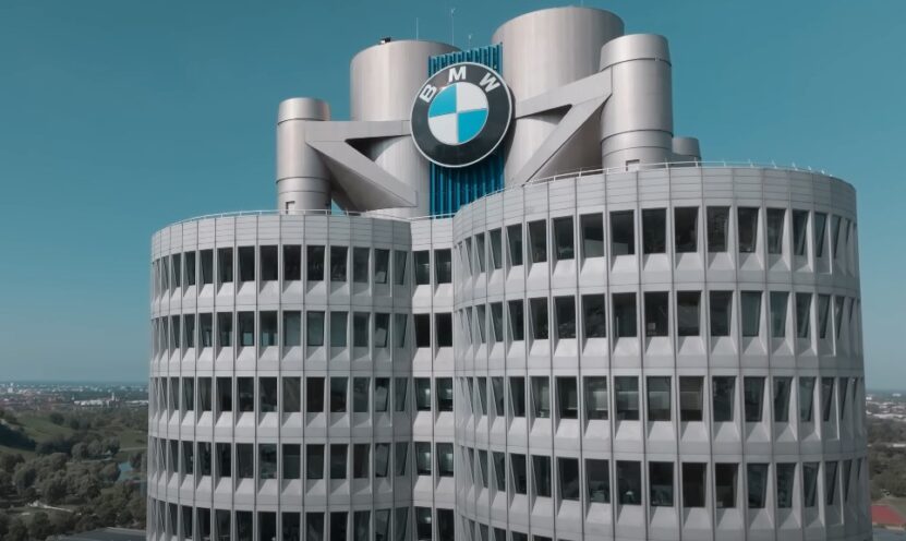 BMW logo displayed prominently on the rooftop of a modern building against a clear blue sky