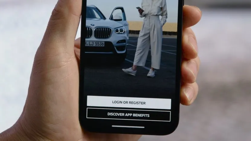 Close-up of a smartphone screen showing the My BMW app with options to log in or discover app benefits