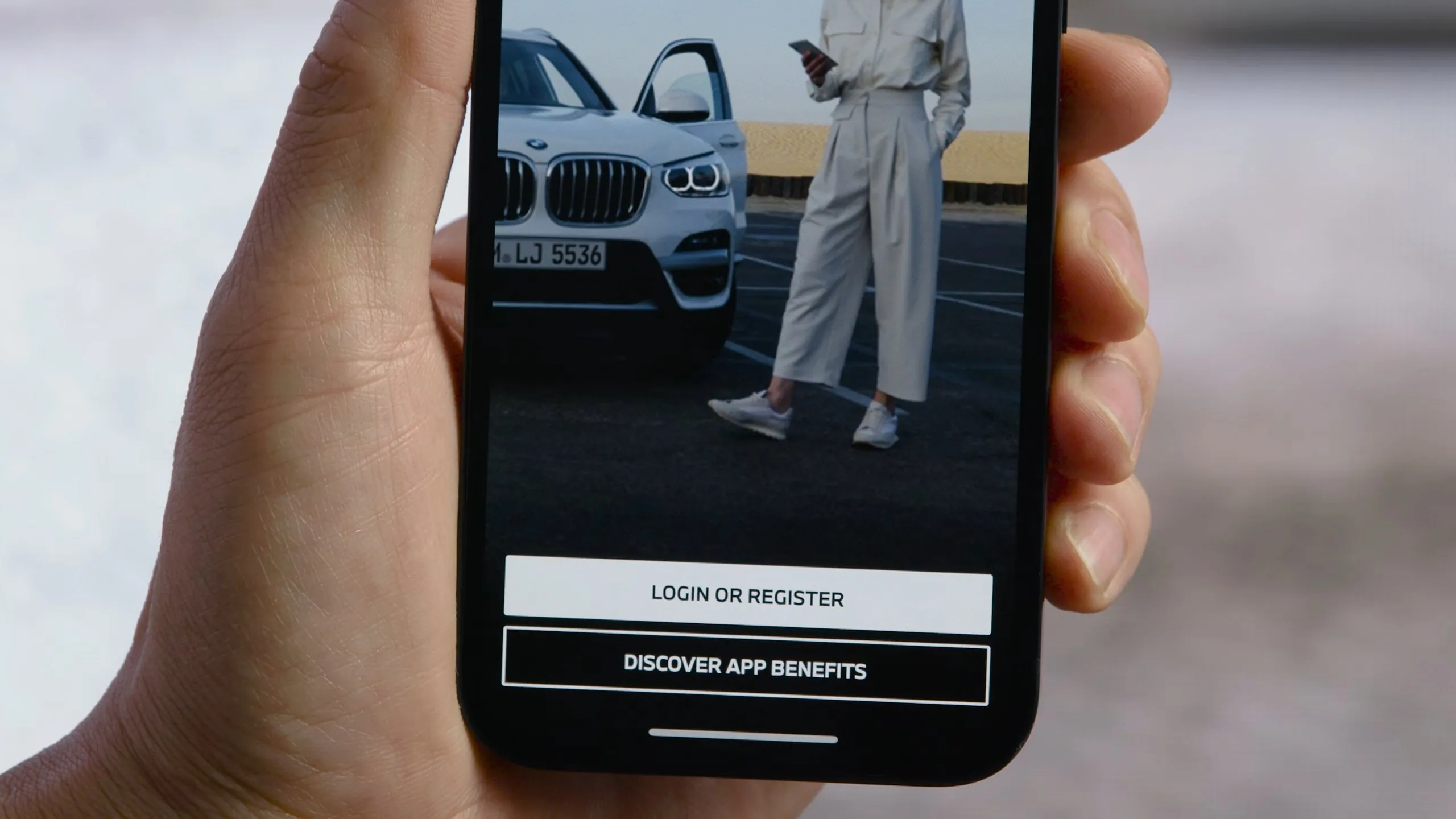 Close-up of a smartphone screen showing the My BMW app with options to log in or discover app benefits