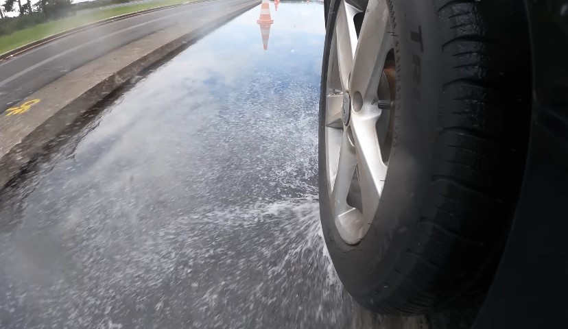 A car tire navigates a flooded road section