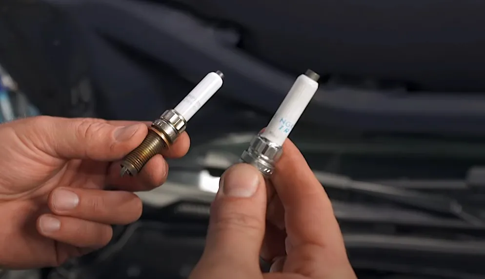 Two hands holding BMW spark plugs