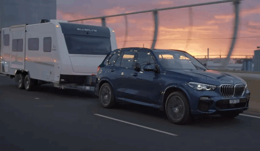 BMW SUV towing RV on a sunset