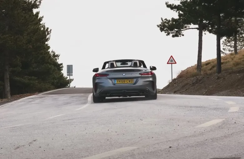 A gray convertible BMW Z4 navigates a winding mountain road