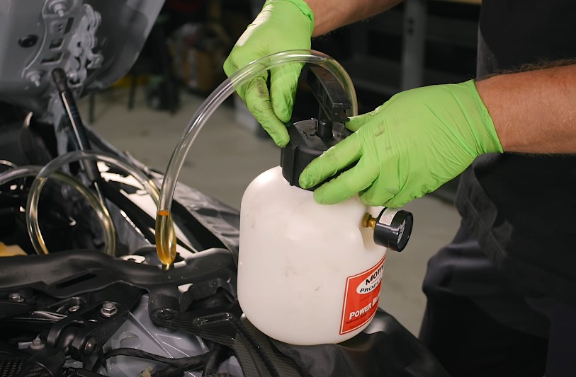 Replacing brake fluid. The old fluid is being collected and removed
