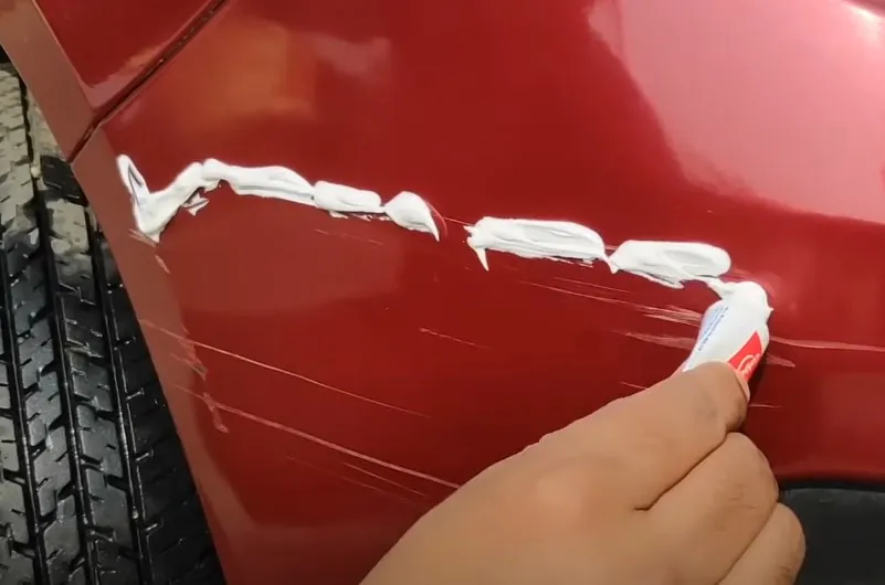 White paste fills the scratches on the red car panel
