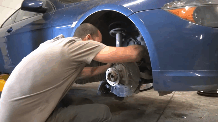 Mechanic works on the front suspension of an E63 BMW 6 Series, addressing common steering and handling issues