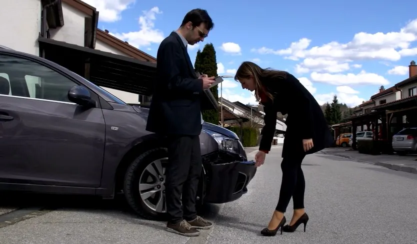 Insurance adjuster and representative examining the car's front end
