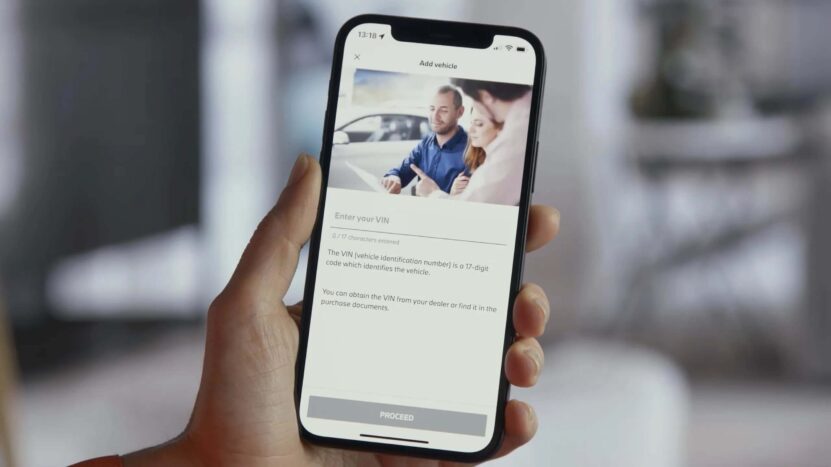 Close-up of a smartphone screen showing the VIN entry screen on the My BMW app, with a couple receiving assistance at a dealership