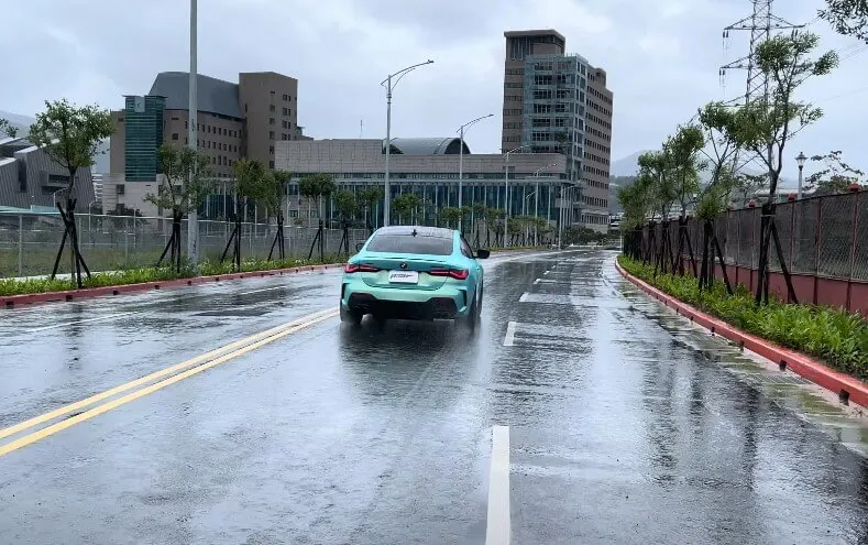 BMW M440i driving down a wet street during rain