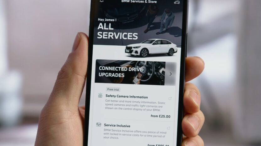 Close-up of a smartphone showing the BMW Services & Store screen, highlighting ConnectedDrive Upgrades with subscription options like Safety Camera Information