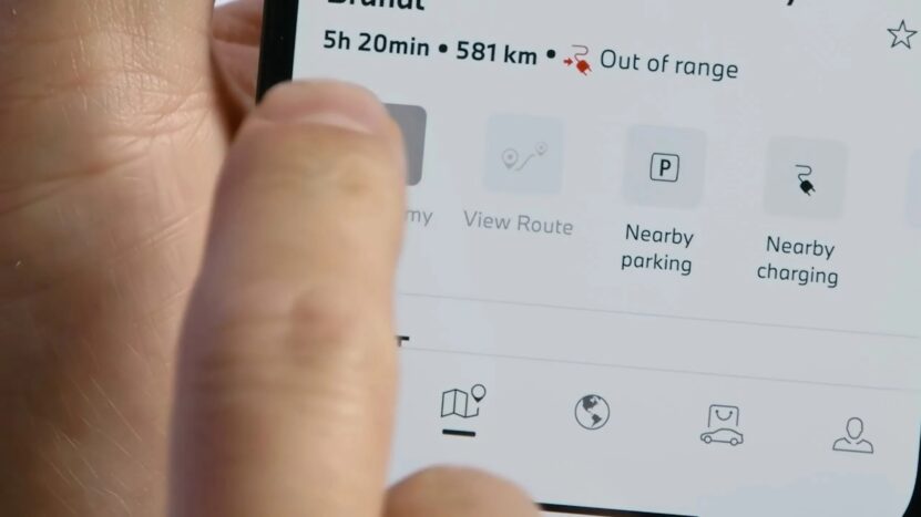 Close-up of a smartphone screen displaying the BMW app with a route status showing "Out of range" and options like Nearby Parking and Charging