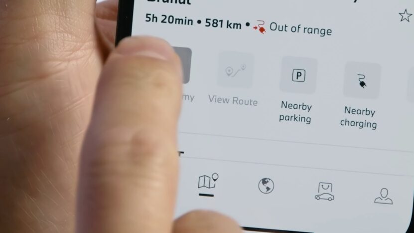Close-up of a smartphone screen displaying the BMW app with a route status showing "Out of range" and options like Nearby Parking and Charging