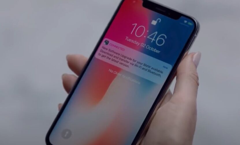 A ConnectedDrive notification appears on a smartphone, prompting a software update