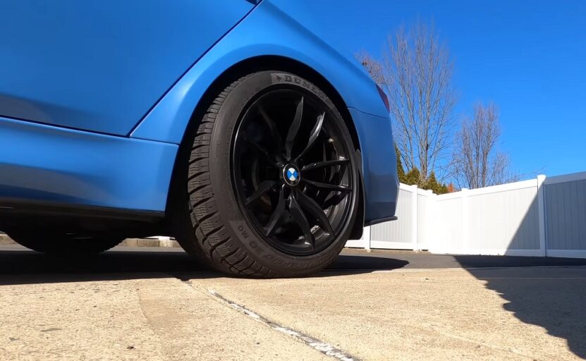 Matte blue BMW parked on pavement with sleek black alloy wheels fitted with run-flat tires