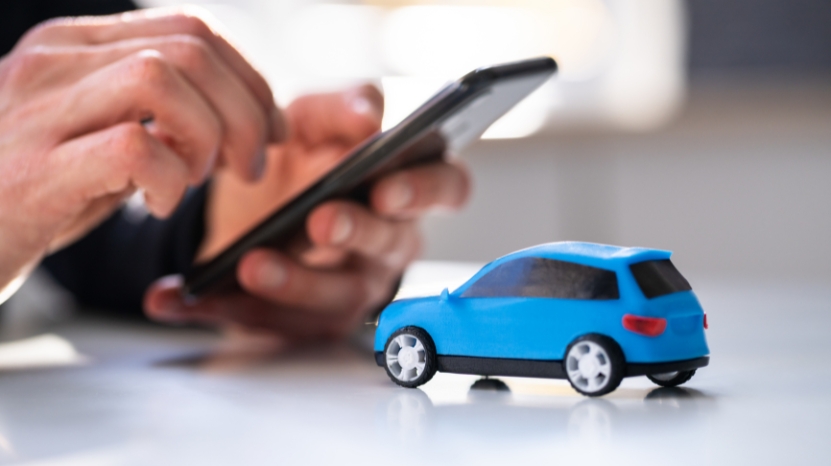 Person using phone next to toy car, showing tech use in car buying