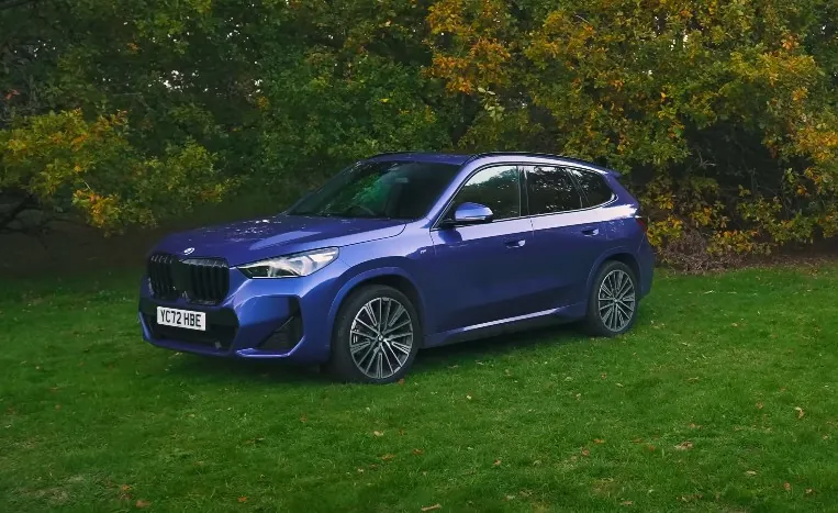 A vibrant, deep-blue BMW X1 SUV sits poised on a lush green lawn