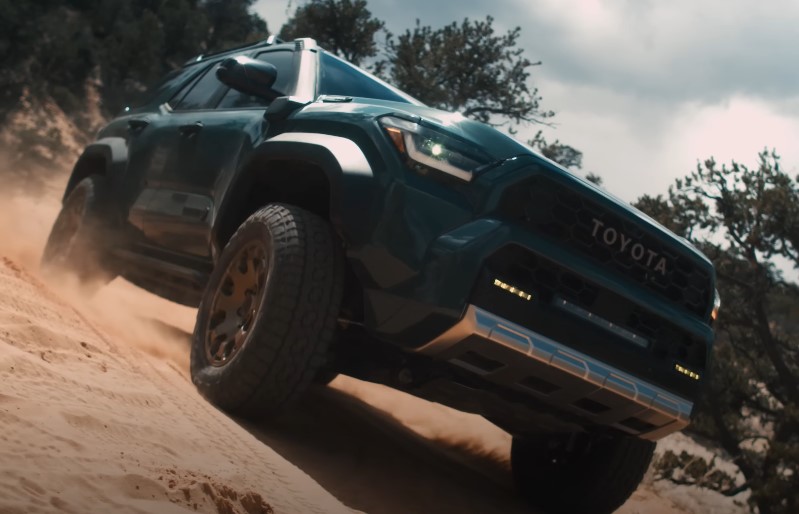 A teal Toyota 4Runner ascends a sandy incline