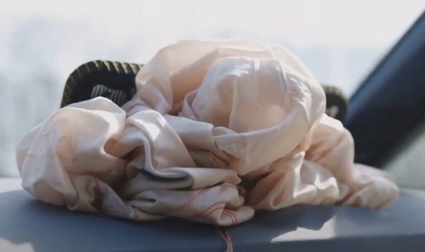 The airbag, a muted beige, rests on a gray surface