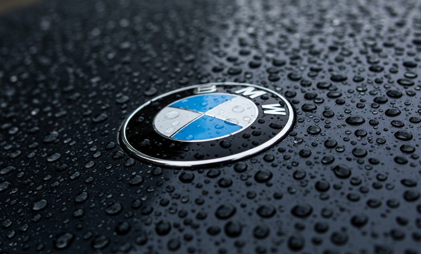 Close up view of BMW logo on a black hood, covered in raindrops