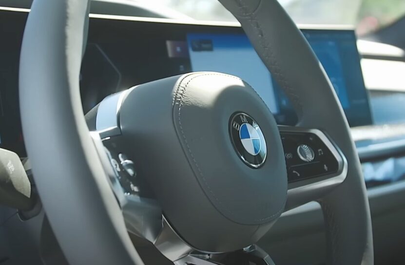 Close-up of a modern car's steering wheel, showcasing the BMW logo and integrated controls