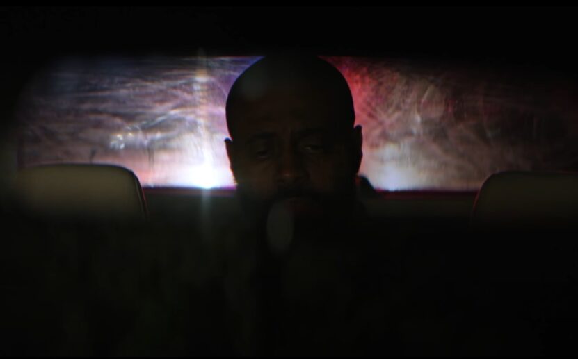 Intense focus on the man's face, set against a backdrop of shifting, colorful police light