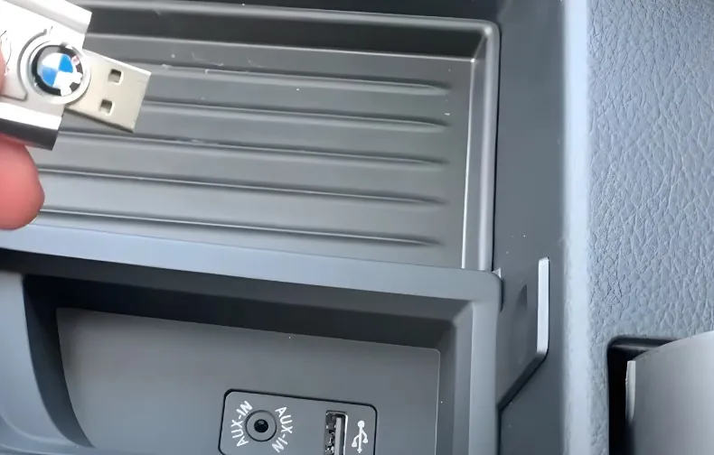 BMW-branded USB drive inserted into the car's auxiliary input