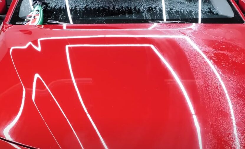 Sparkling red, freshly washed car hood, soap suds glistening
