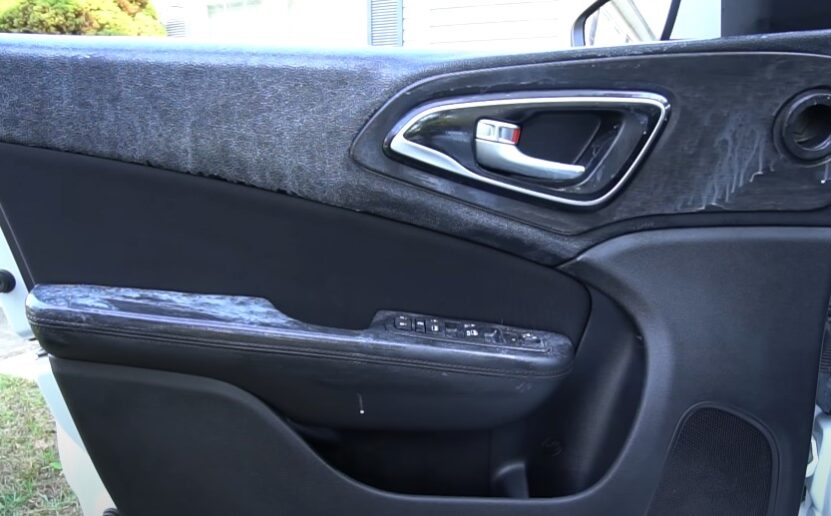 A car door panel, marred by time and grime, whispers tales of journeys past