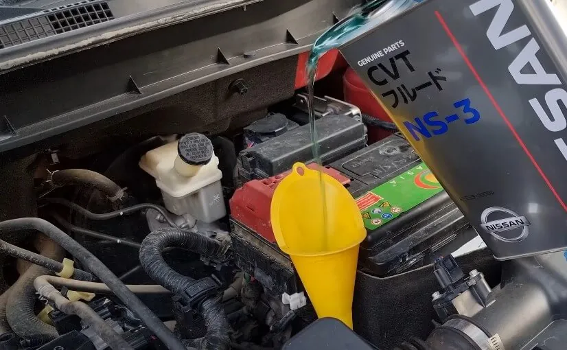 Fluid being poured into a car's engine compartment