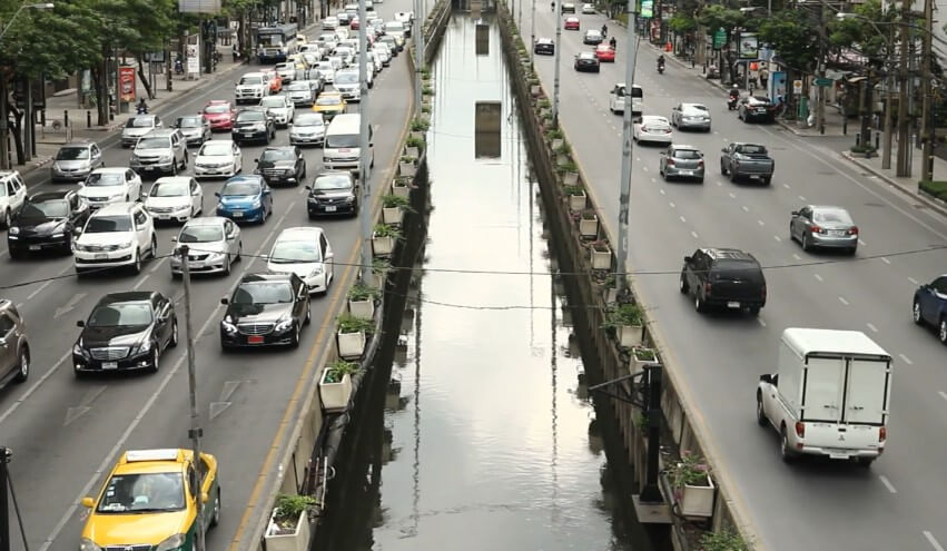 A bustling city street, choked with vehicles navigating a canal
