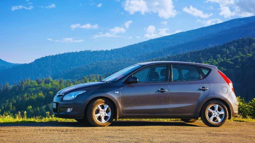 Grey hatchback parked on a sunny mountain road