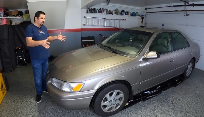 A man demonstrates car maintenance in a garage